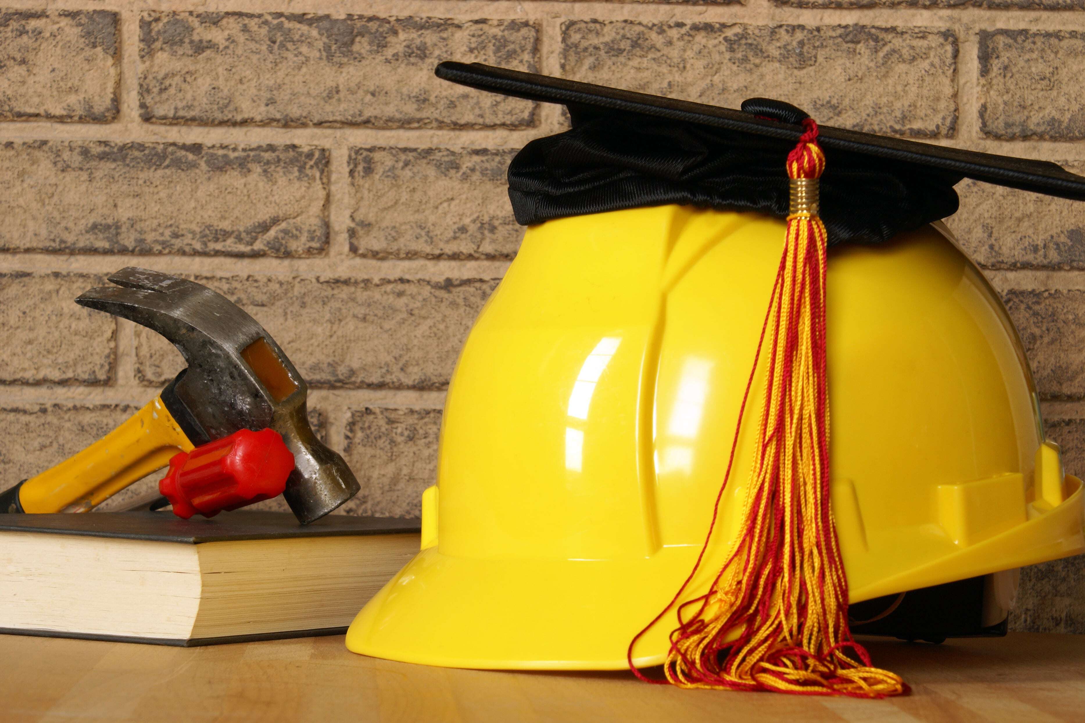 construction safety education yellow hard hat and tassle, hammer, smart hand tools