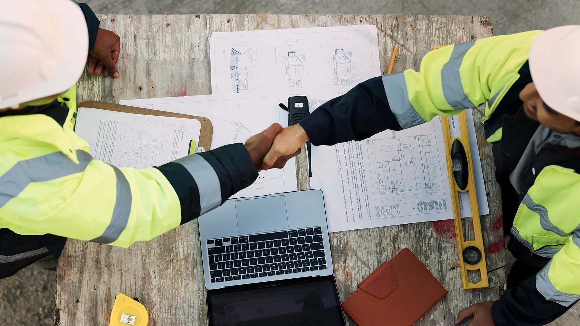 two professionals discussing building plans, shaking hands on a deal